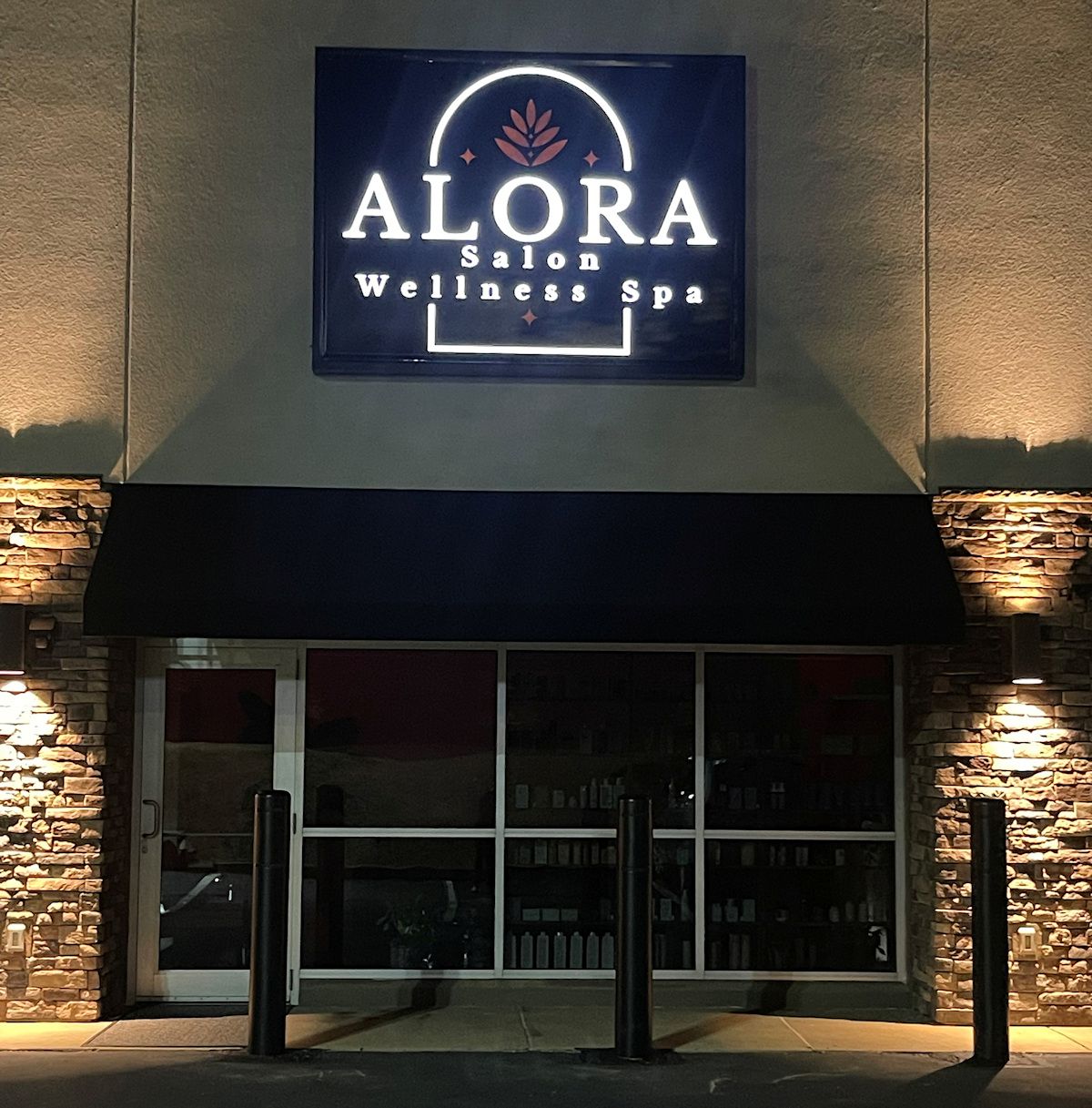 The lit ALORA Salon & Wellness Spa sign above the stone storefront on Chauvet Drive, Robinson Township, Pittsburgh