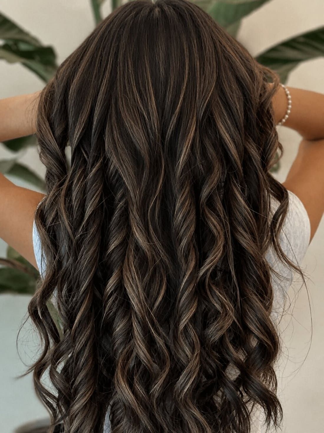 Long brunette hair with dimensional highlights, finished in loose waves at Alora Salon in Robinson Township
